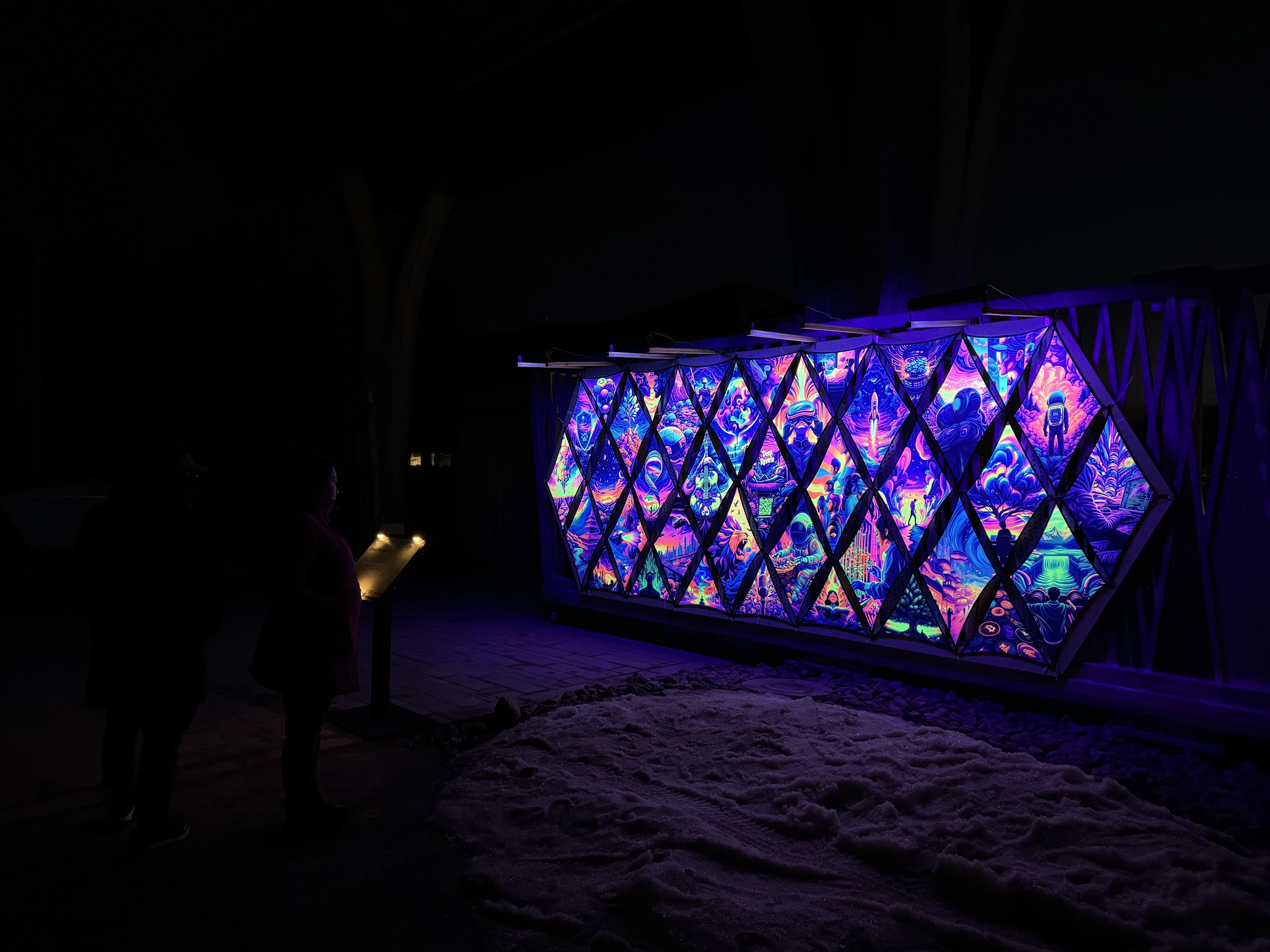 Deep Reverie's vivid neon artwork glowing in a geometric outdoor frame at night